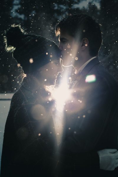 Couple kisses in snow with backlit lighting in Custer State Park, SD