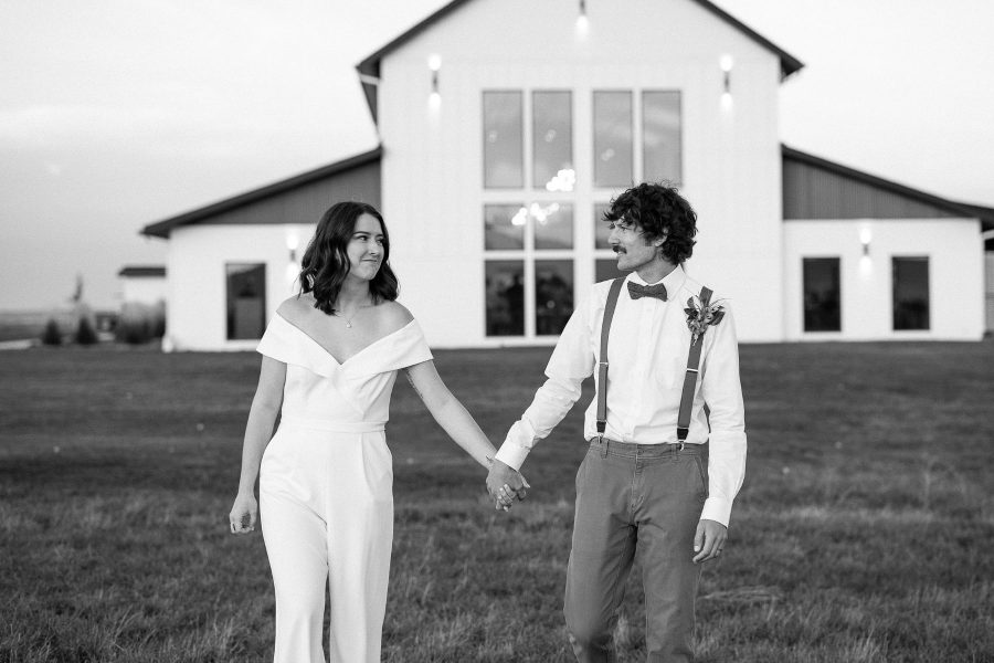 Couple walk hand in hand in front of the Barn at Aspen Acres