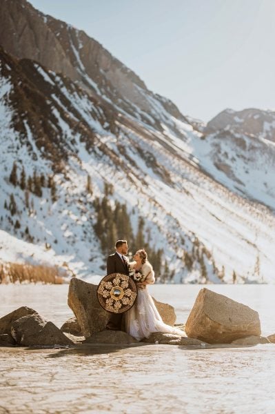 Elopement on frozen lake at Convict Lake. Couple in wedding attire on frozen lake.