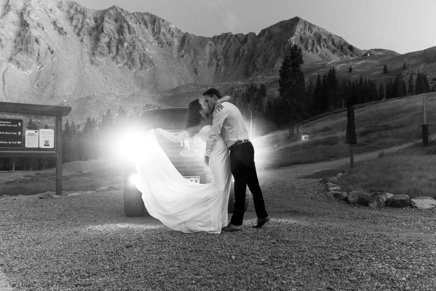 Breckinridge elopement, Arapahoe basin ski lift. Couple in front of car with headlights on, dancing.