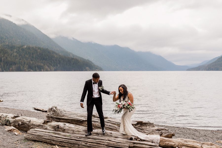 Groom leading a bride over a log at Lake Crescent