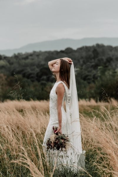 Whimsical boho bride poses in front of mountains