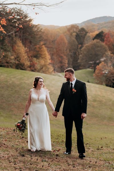 Bride and Groom walk holding hands at Sampson's Hallow Wedding Venue in the Smoky Mountains