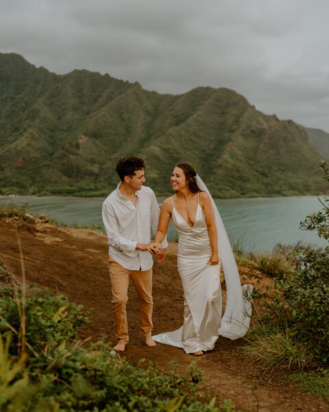 Bride and groom eloping in Hawaii with beach and mountain range in the background.