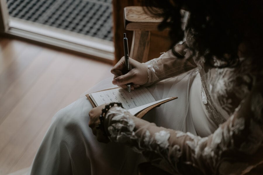 A bride writing vows in a book.