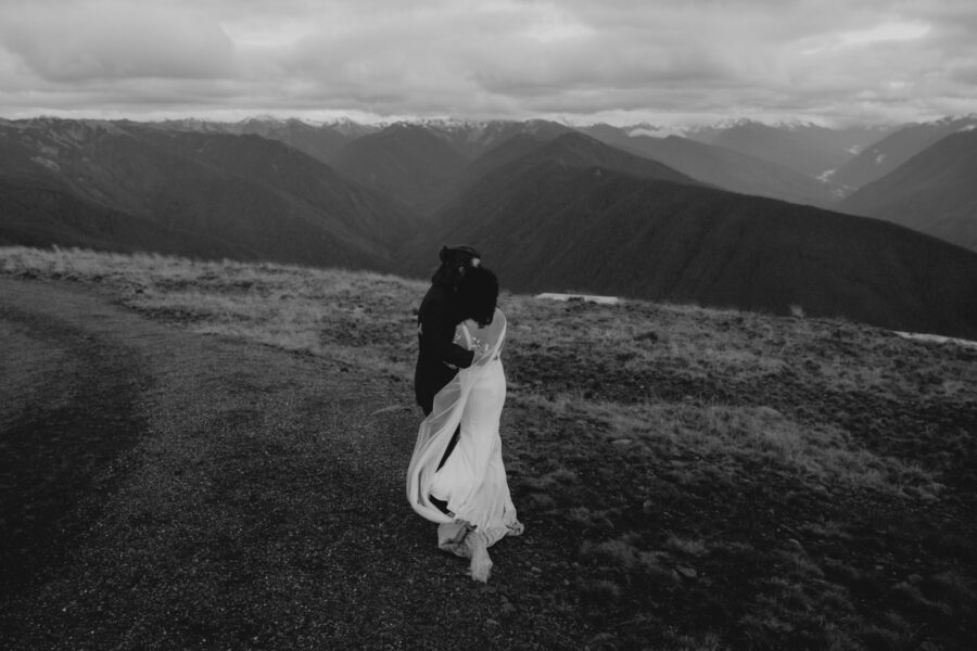 A bride and groom bracing against the wind of the mountain.