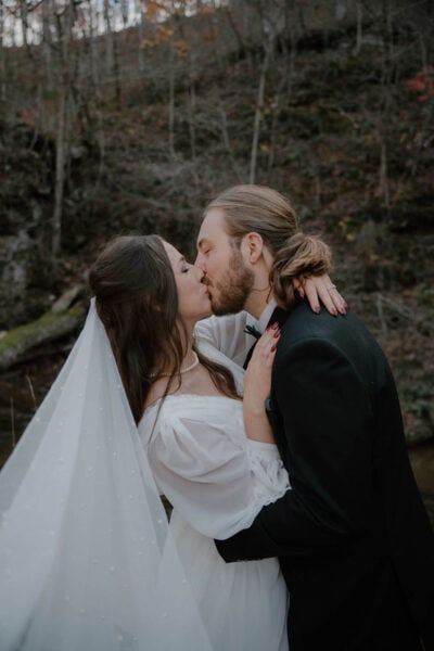 photo of bride and groom kissing in the woods