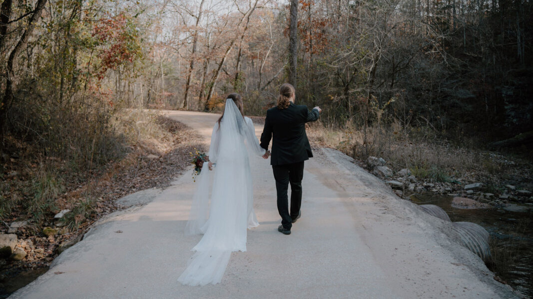 photo of bride and groom walking down a dirt path in the woods forrest