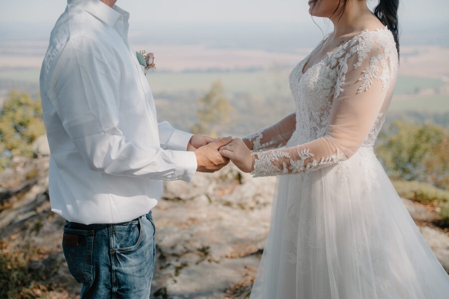 Photo of bride and groom holding hands on a mountaintop