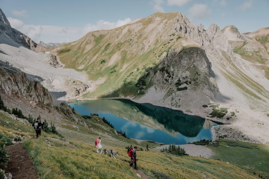bride and groom hiking above an alpine lake