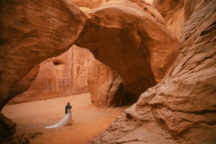 Just married couple walking under the Sand Dune Arch