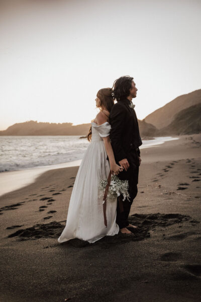 Bride’s flowing dress captured beautifully on a windy black sand beach in San Francisco