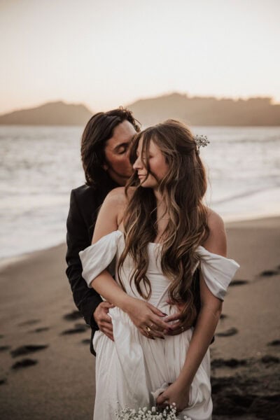 Candid moment of a couple walking barefoot along a black sand beach in San Francisco during their elopement.