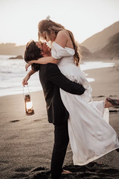 couple sharing a kiss on black sand beach in San Francisco, california
