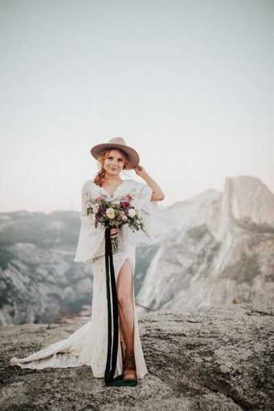 Adventurous bride hiking in her wedding dress along a scenic glacier point in yosemite