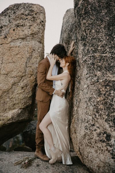 Couple standing on Glacier Point, overlooking Yosemite Valley during their adventurous elopement