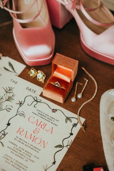 Elopement details like ring box, invitation, jewelry, shoes, on a rustic wooden background