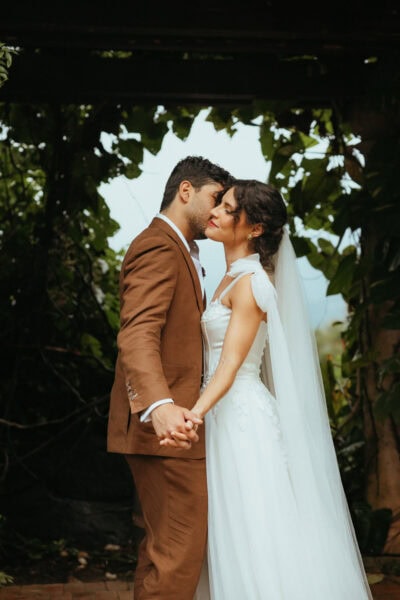 Man and Woman standing together after getting married, with the groom kissing his bride's cheek