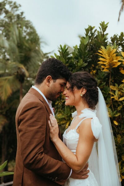 Man and Woman standing together after getting married, smiling at each other with their foreheads touching