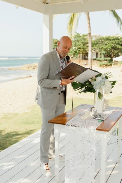 Officiant to wedding ceremony reading prepared sentiments from a book