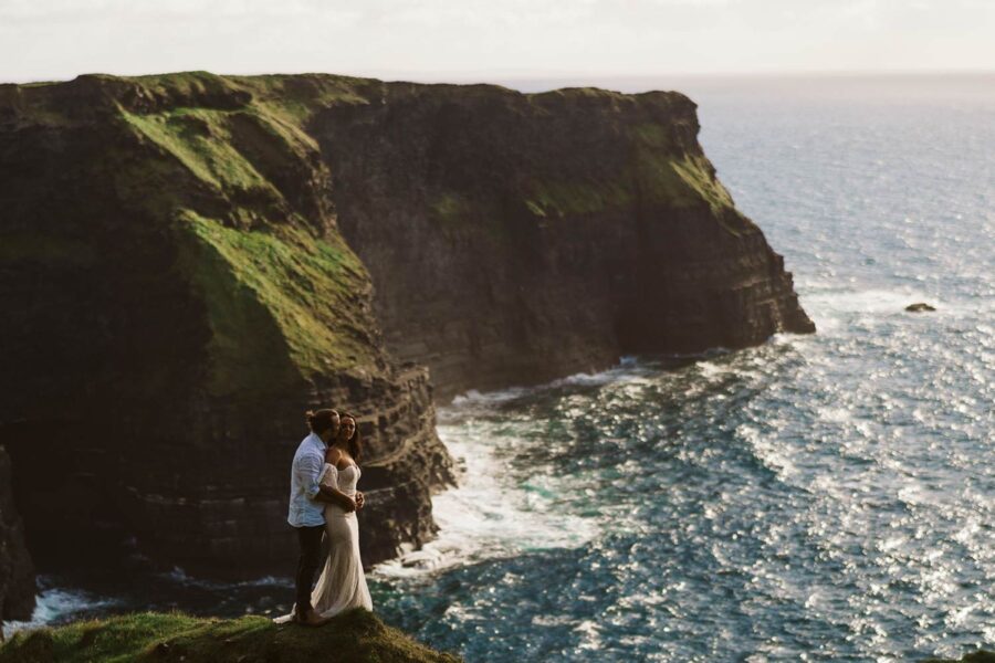 Couple eloping on cliffs in Ireland with arms around each other