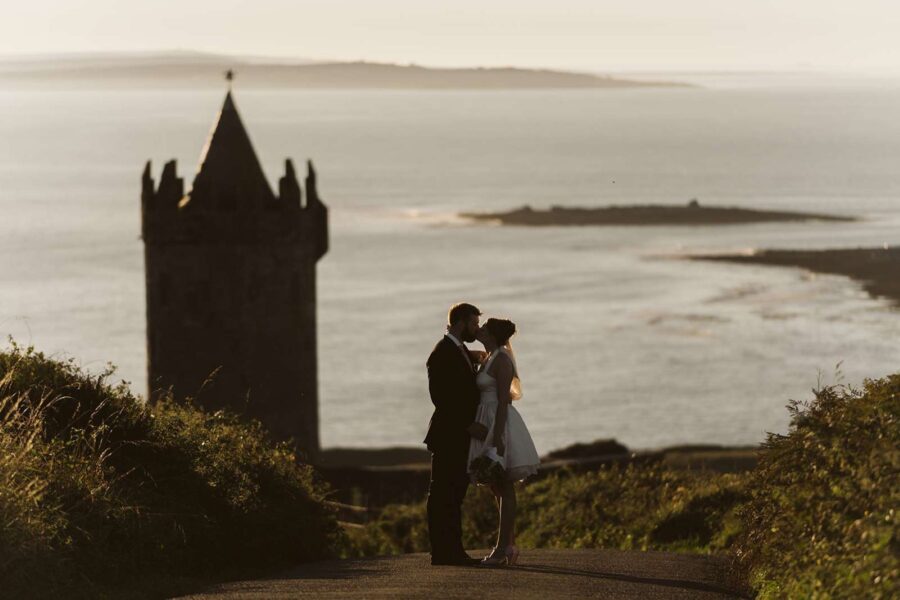Couple kissing at castle ruin at sunset in Ireland