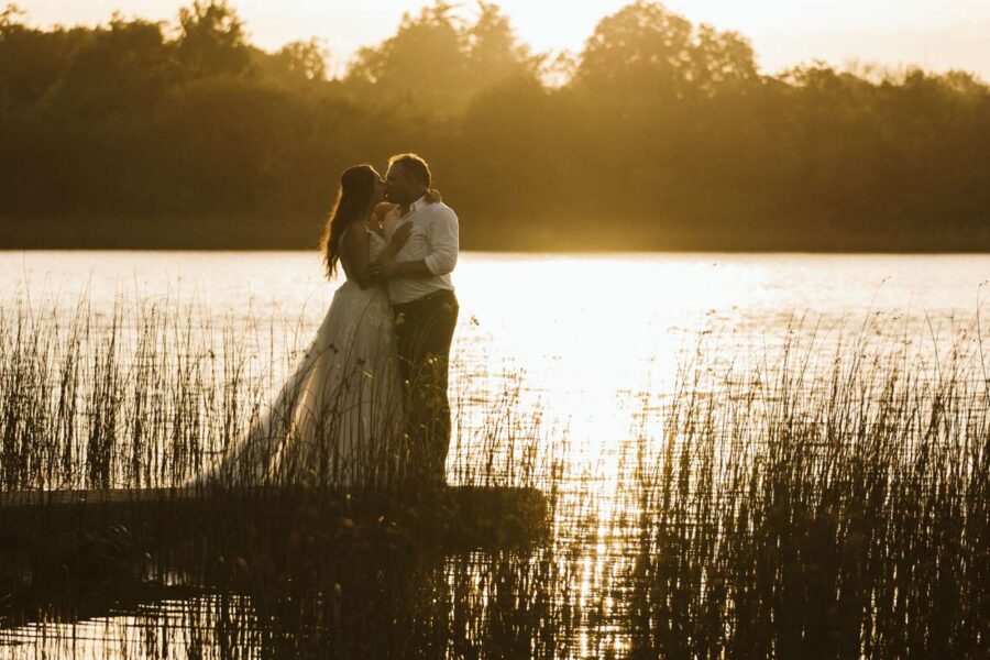 Couple eloping on a pier in Ireland at sunset, with arms around each other