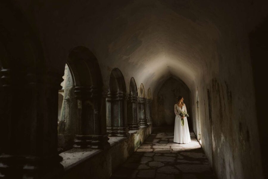 A bride in low light in an abbey ruin while eloping in Ireland